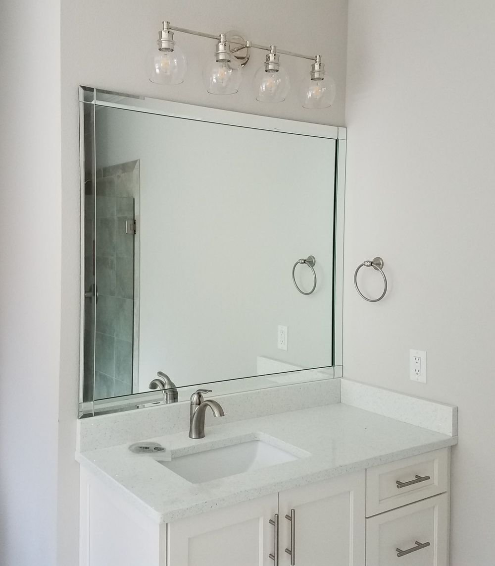 Framed mirror installed above a bathroom vanity
